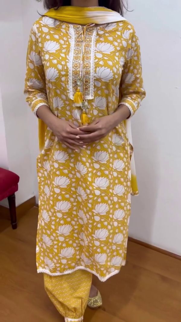 Bright Mustard Yellow Floral Printed Cotton Kurta Set for Women Featuring White Lotus Motif, Lace Detailing, Embroidered Neckline with Tassels, Matching Pants and Dupatta – Ideal for Festive and Everyday Ethnic Wear