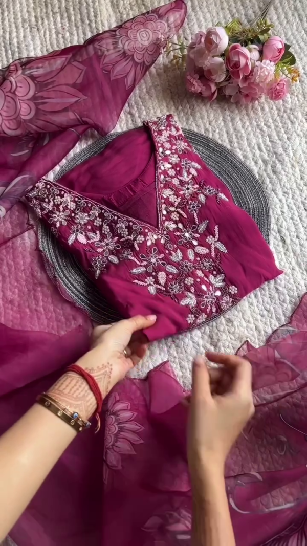 legant magenta suit with intricate floral embroidery on the neckline. Paired with a sheer printed dupatta featuring a bold floral motif