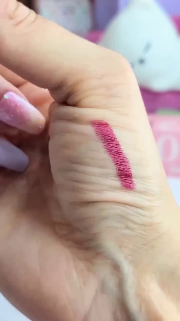 A vibrant orange star-shaped lip balm is being swatched on the hand, leaving a soft, pinkish tint. - Image 2