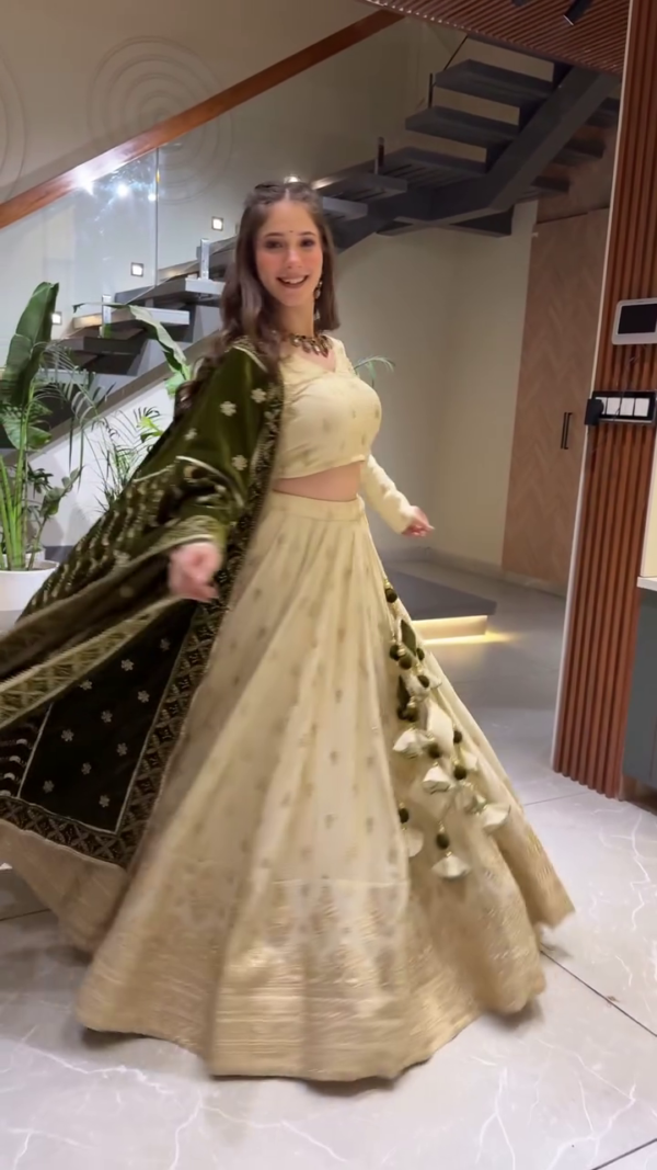 Elegant Cream and Olive Green Ethnic Lehenga Set Featuring Subtle Golden Embroidery, Full-Sleeve Blouse, Rich Woven Dupatta, and Coordinated Latkan Tassels – A Refined Traditional Ensemble Perfect for Engagements, Sangeet Functions, and Festive Celebrations